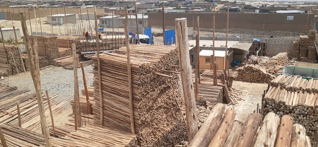 Patio de almacén de Sabinita con postes de madera apilados y personal trabajando